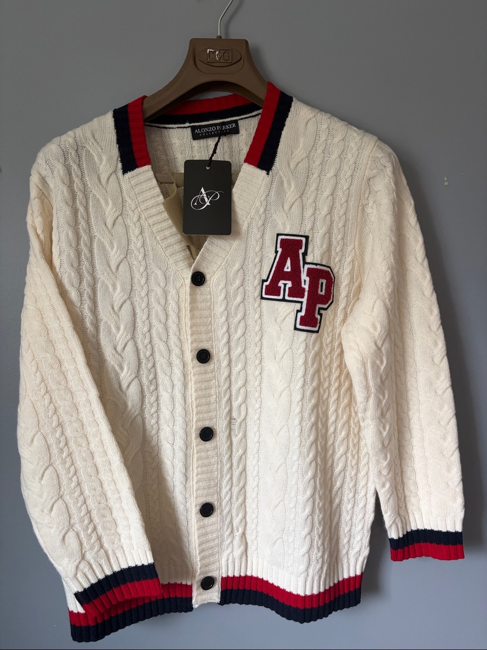 Merino Wool Cream Cable-Knit Cardigan with red and blue accents.